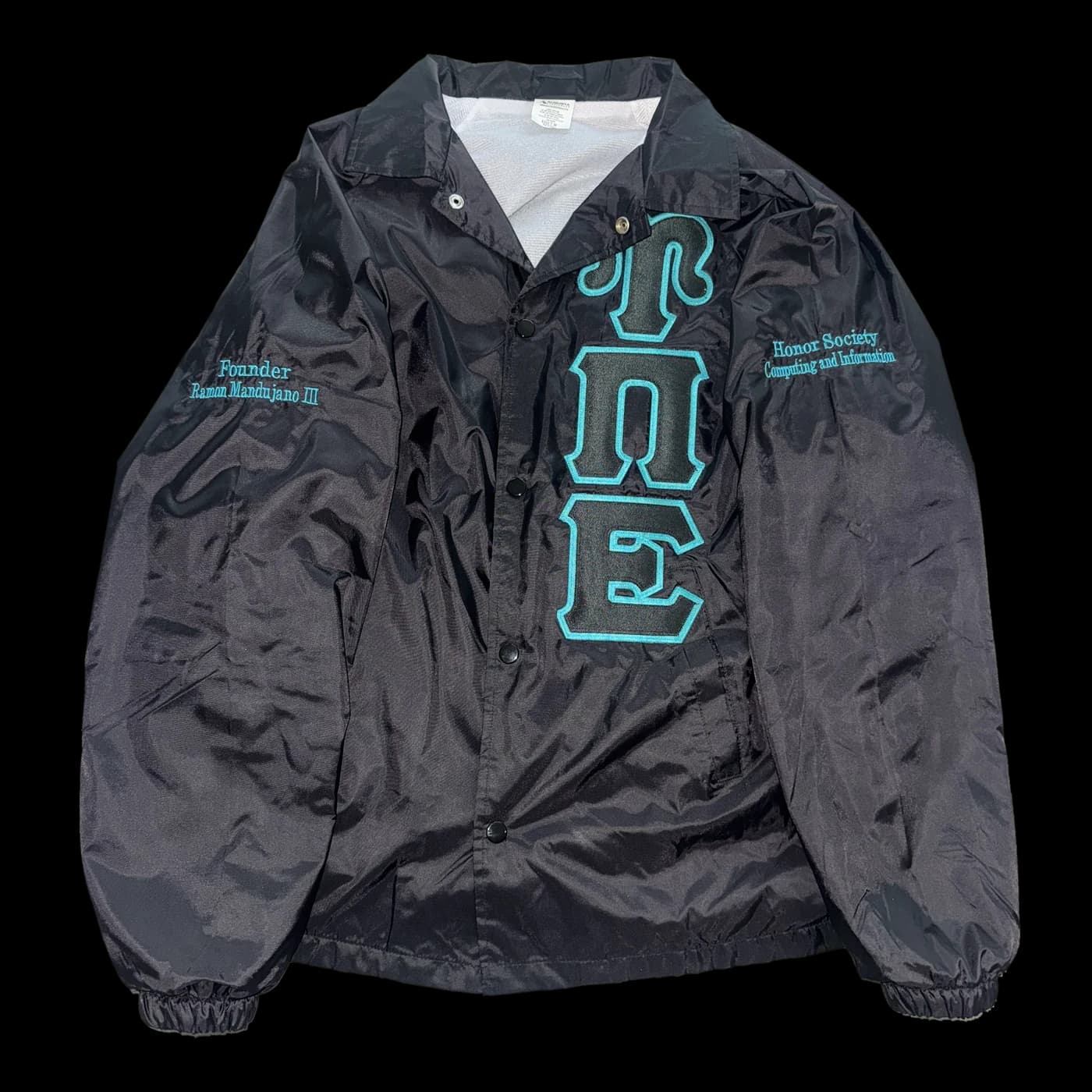 The chapter honor jacket: a black satin jacket with the Upsilon Pi Epsilon letters outlined in teal down the front, 'Honor Society, Computing and Information' on one chest and the founder's name on the other.